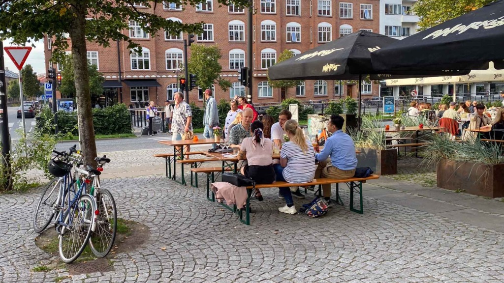 Man sidder ved tr&aelig;borde og p&aring; tr&aelig;b&aelig;nke udenfor hos Stechers